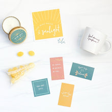 Load image into Gallery viewer, A beautifully arranged gift box designed for special occasions, featuring a vibrant greeting card with the empowering message "She Was Made of Sunlight," a zesty Ray of Sunshine Lemondrops, a calming soy candle, a playful and chic coffee mug, and a set of mini inspirational quote cards. Perfect for celebrating and uplifting your best gal or sending encouragement to someone special, reminding her of her amazing qualities and how much she's loved.