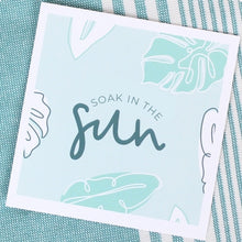 Load image into Gallery viewer, A vibrant greeting card titled "Soak in the Sun" from the "Spa" gift box. The set also includes a zesty Ray of Sunshine Lemondrop, a calming soy candle, and an exfoliating sugar whip scrub, all curated to provide a relaxing and rejuvenating spa experience.