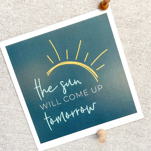 A greeting card titled "The Sun Will Come Up Tomorrow" from the "Get Well or Cozy" gift box. The set also includes cheerful Ray of Sunshine Lemondrops, comforting Chicken Noodle Soup (Serves 10), soothing Cup of Sunshine Tea Bags (10), a Mini Honey Bear, and Swizzle Sticks, offering warmth and comfort in a thoughtful gift ensemble